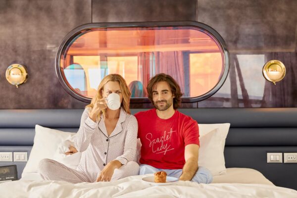 A couple enjoys breakfast in bed in the Brilliant Suite. Photoshoot of Vitamin Sea activities by Melanie Acevedo onboard Scarlet Lady, Virgin Voyages 